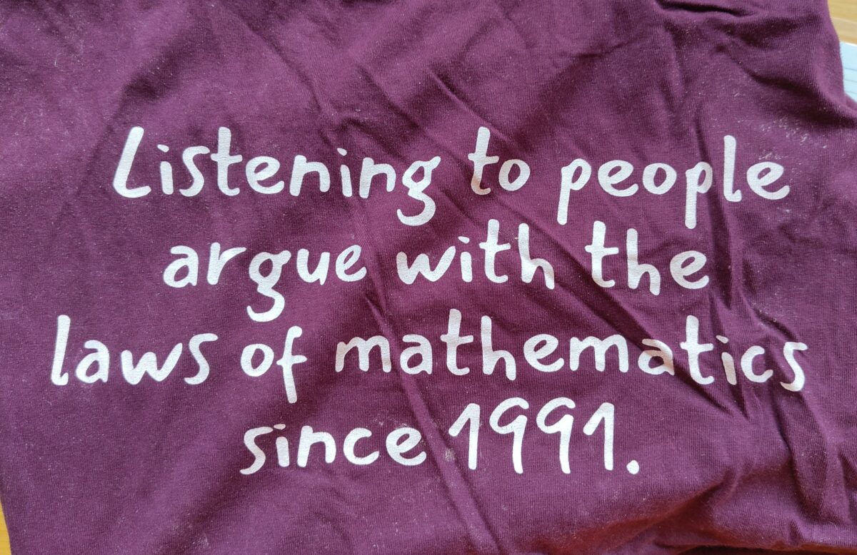 Purple T-shirt displaying, in white, the words, "Listening to people argue with the laws of mathematics since 1991".