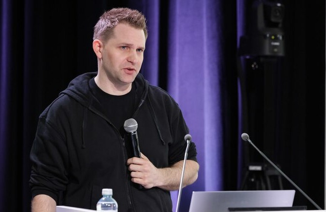 Max Schrems in 2024, a white man in a black hoodie holding a mic.