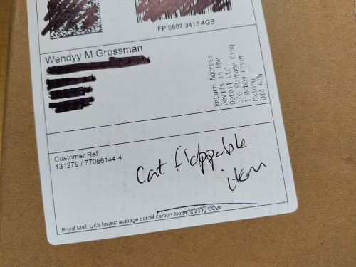 Part of a Royal Mail address label showing the handwritten words, "cat flappable item".