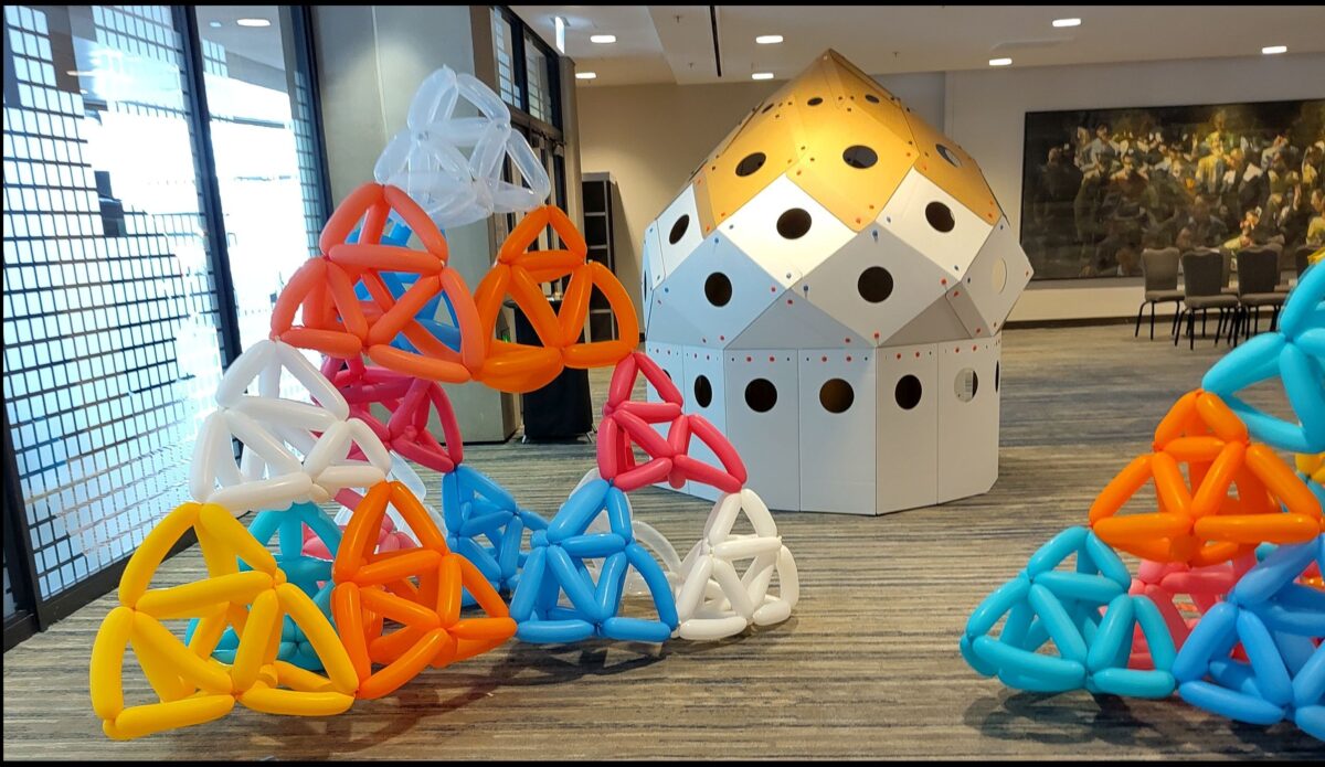 Two Sierpinski tetrahdrons made of long, colorful balloons and a might-be polar zonahedron in yellow and white.